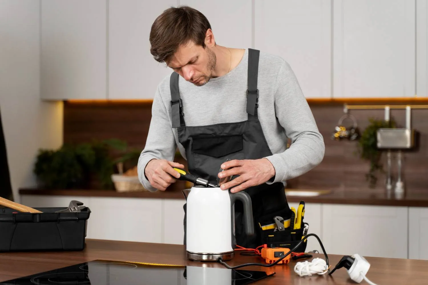 Technician repairing an electric kettle on a kitchen counter
